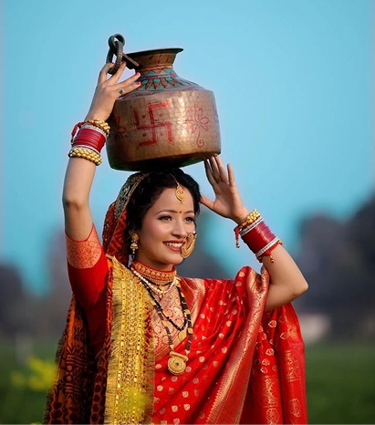 Woman in traditional red attire carrying a kalash